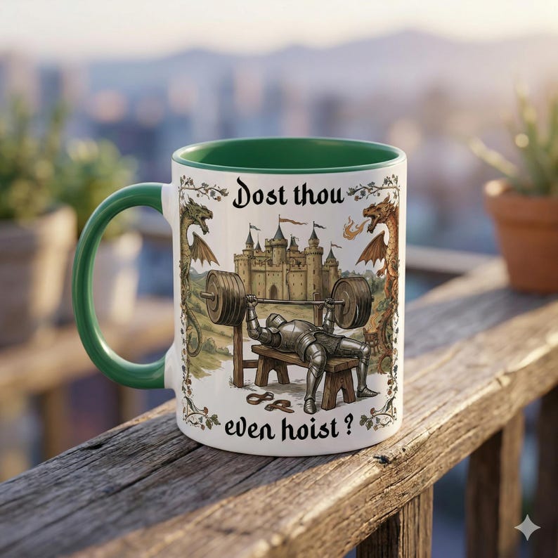 May include: White ceramic mug with a green handle and rim, featuring a medieval knight bench pressing a barbell. The mug has a castle and dragon design with the text "Dost thou even hoist?"