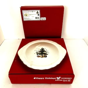 Peut inclure: Un bol à légumes en céramique blanche avec un bord doré et un motif d'arbre de Noël. Le bol mesure 25,4 cm de diamètre et est fabriqué au Japon. Le bol est dans une boîte rouge avec les mots "Joyeuses Fêtes" et "Nikko" imprimés dessus.