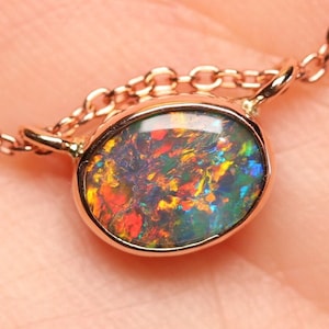 Puede incluir: Un delicado collar de cadena de oro con un pequeño colgante de ópalo ovalado. El ópalo es una mezcla vibrante de rojo, naranja, verde y azul.