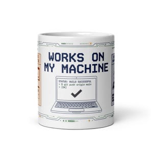 Könnte beinhalten: Weißer Keramikbecher mit dem Text "WORKS ON MY MACHINE" in Blau, einer Laptop-Grafik und dem Status "BUILD SUCCESSFUL". Der Becher hat ein technikbasiertes Design.