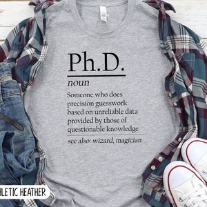 May include: A heather grey t-shirt with the text "Ph.D." defined as "Someone who does precision guesswork based on unreliable data provided by those of questionable knowledge. See also: wizard, magician."