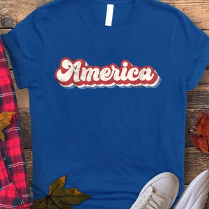 May include: A blue t-shirt with a red, white, and blue retro-style graphic that says "America".