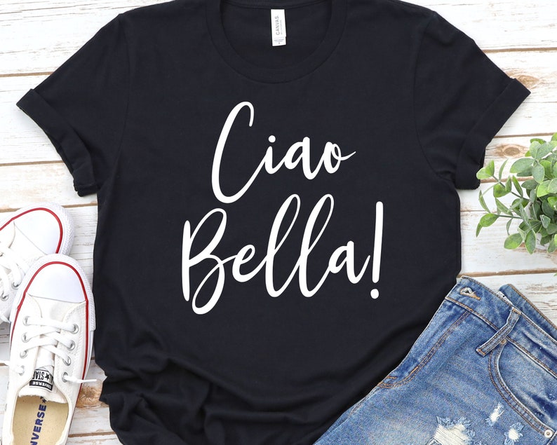 K&ouml;nnte beinhalten: Schwarzes T-Shirt mit dem Schriftzug "Ciao Bella!" in wei&szlig;er Schrift. Das Shirt wird mit blauen Jeansshorts und wei&szlig;en Turnschuhen kombiniert. Ein l&auml;ssiges und stilvolles Outfit.