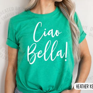 K&ouml;nnte beinhalten: Ein leuchtend gr&uuml;nes T-Shirt mit dem Schriftzug "Ciao Bella!" in wei&szlig;er Schrift. Das Shirt hat kurze &Auml;rmel und eine lockere Passform. Der Text ist mittig auf der Vorderseite platziert.