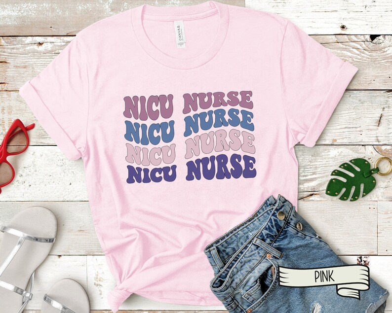 May include: Pink t-shirt with the text "NICU NURSE" repeated four times in a retro font. The text is in shades of purple, blue, and pink.