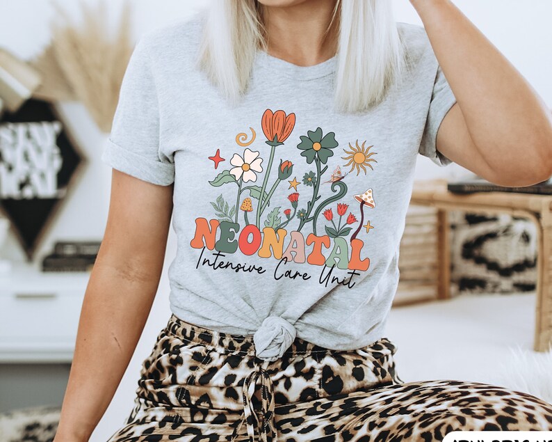 May include: Grey t-shirt with a floral design and the text "Neonatal Intensive Care Unit" in colorful letters.