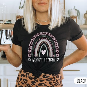 May include: Black t-shirt featuring a rainbow design and the text "Daycare Teacher".