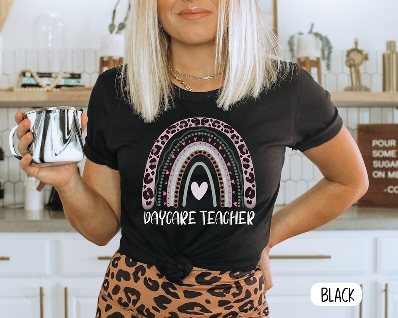 May include: Black t-shirt featuring a rainbow design and the text "Daycare Teacher".