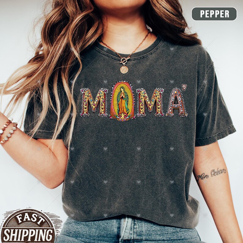 May include: A gray t-shirt with the word "MOMA" in rhinestones. The "O" is a depiction of the Virgin Mary.