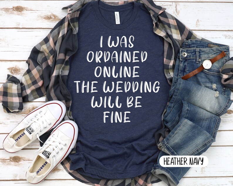 May include: A heather navy blue t-shirt with the text "I was ordained online the wedding will be fine" in white lettering.