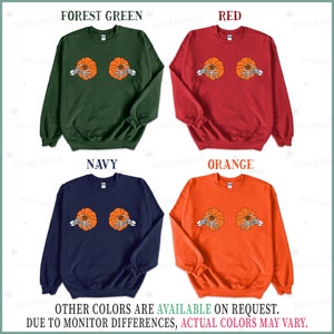 Op de afbeelding: Vier sweatshirts met een pompoenprint. De sweatshirts zijn in bosgroen, rood, marineblauw en oranje. De tekst "OTHER COLORS ARE AVAILABLE ON REQUEST. DUE TO MONITOR DIFFERENCES, ACTUAL COLORS MAY VARY." staat onderaan de afbeelding.