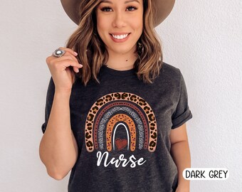 May include: A dark grey t-shirt with a rainbow design featuring leopard print and a heart. The text "Nurse" is printed below the rainbow.