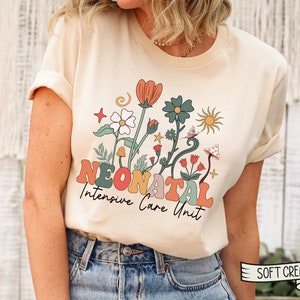 May include: A cream colored t-shirt with a retro floral design and the text "Neonatal Intensive Care Unit".
