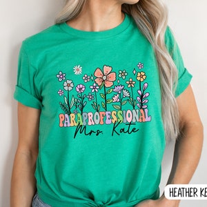 May include: Green t-shirt with a colourful floral design and the text "Paraprofessional Mrs. Kate".
