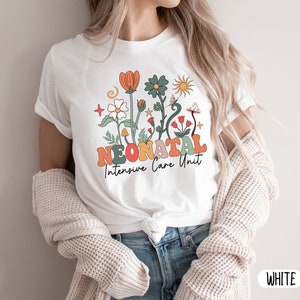 May include: White t-shirt with a floral design and the text "Neonatal Intensive Care Unit".