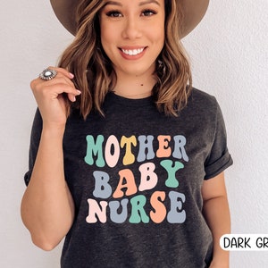 Może przedstawiać: Ciemnoszary T-shirt z napisem "MOTHER BABY NURSE" w kolorowych retro literach.