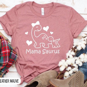 May include: Heather mauve t-shirt with a white graphic of two dinosaurs with hearts and the text "Mama Saurus".