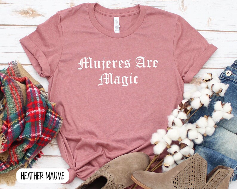 May include: Heather mauve t-shirt with the text "Mujeres Are Magic" in white lettering.