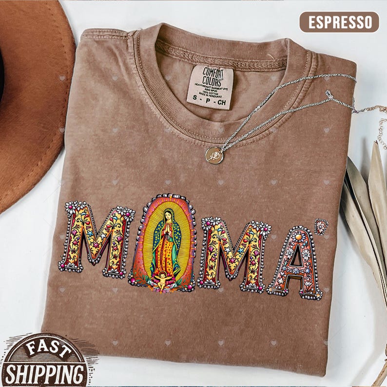 May include: A brown t-shirt with a floral design that spells out "MOMA" with a depiction of the Virgin Mary in the center. The shirt has a distressed look and is made of a soft, comfortable material.