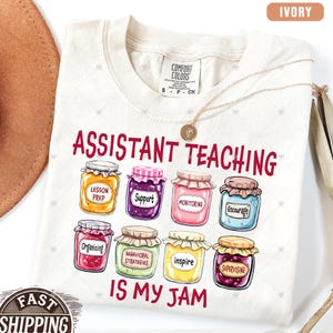 Puede incluir: Camiseta de color marfil con el texto "Assistant Teaching is my jam" y un gr&aacute;fico de tarros con diferentes etiquetas como "Preparaci&oacute;n de la lecci&oacute;n", "Apoyo", "Monitoreo", "Animar", "Organizar", "Estrategias conductuales", "Inspirar" y "Supervisar".