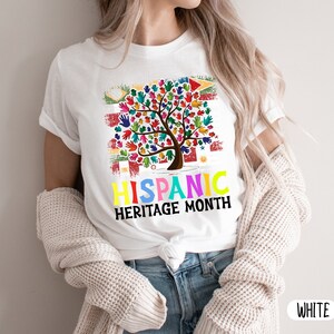 May include: White t-shirt with a colorful tree made of handprints and the text "Hispanic Heritage Month".