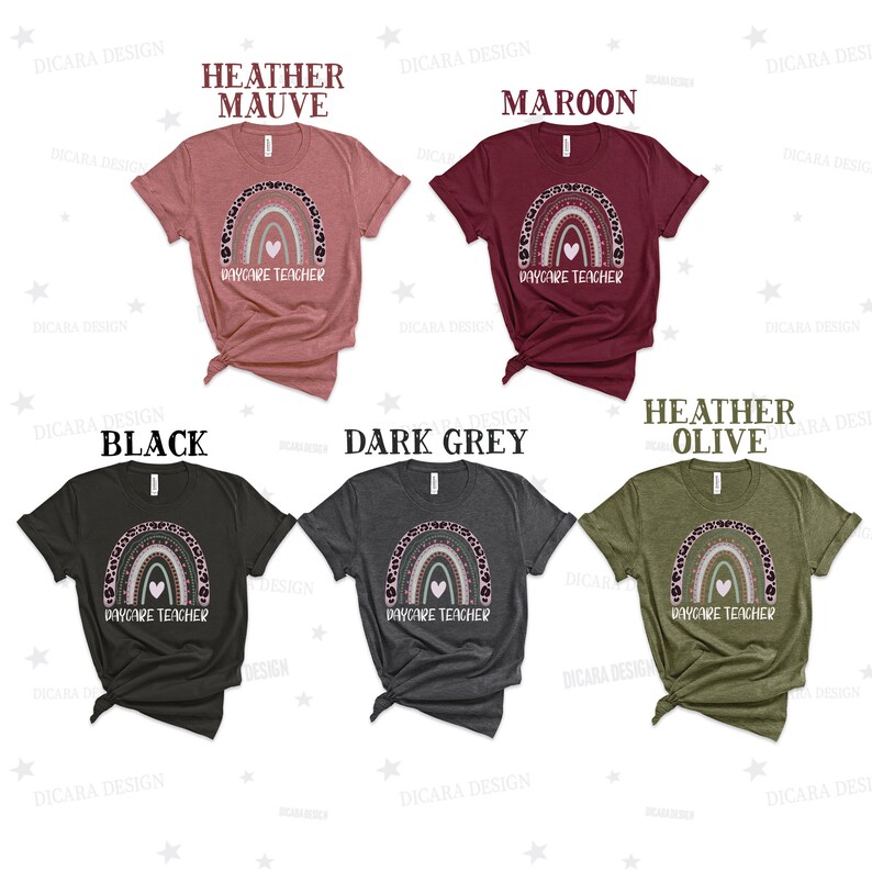 May include: Six t-shirts in different colours with a rainbow and heart design and the text "Daycare Teacher". The colours are heather mauve, maroon, black, dark grey, and heather olive.