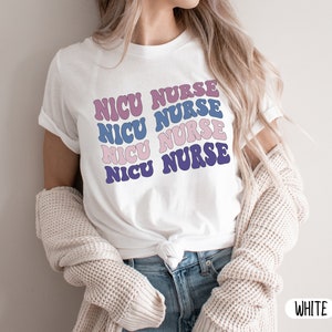 May include: White t-shirt with the text "NICU NURSE" repeated four times in a retro font with purple, pink, and blue colors.