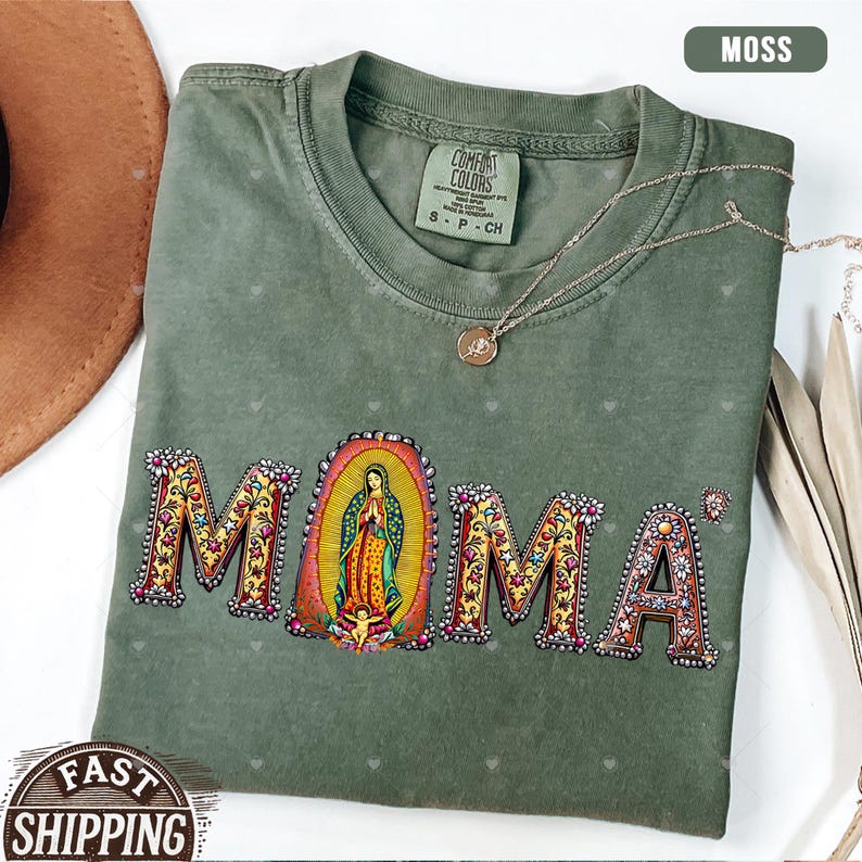 May include: A green t-shirt with the word "MAMA" spelled out in colorful letters with floral designs. The letter "M" has a depiction of the Virgin Mary in the center.