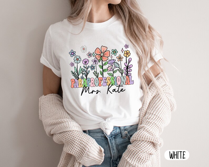 May include: White t-shirt with a colourful floral design and the text "Paraprofessional Mrs. Kate"