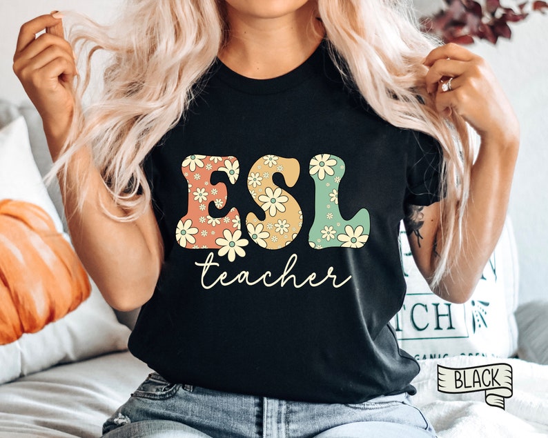 May include: Black t-shirt with the text "ESL teacher" in large, colorful letters with a floral pattern. The letters are in a retro style.