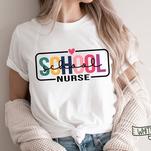 May include: White t-shirt with a colorful graphic that says "SCHOOL NURSE" with a pink heart above the text.
