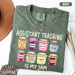 Puede incluir: Una camiseta verde con el texto "Assistant Teaching is my jam" y un gr&aacute;fico de tarros de mermelada con palabras como "Lesson Prep", "Support", "Monitoring", "Encourage", "Organizing", "Behavioral Strategies", "Inspire" y "Supervising" en ellos.