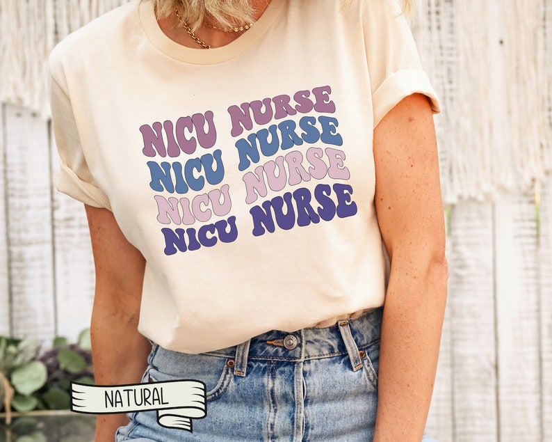May include: A white t-shirt with the text "NICU NURSE" repeated four times in a retro font. The text is in shades of purple and blue.