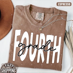 Op de afbeelding: Een bruin T-shirt met de tekst "FOURTH grade" in wit met zwarte letters. Het shirt is in een vintage stijl met een distressed look.
