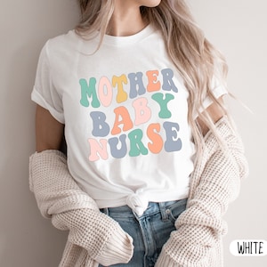 Może przedstawiać: Biała koszulka z napisem "Mother Baby Nurse" w kolorowej czcionce retro.