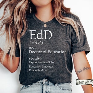 May include: Dark grey heather t-shirt with the text "EdD" and the definition "Doctor of Education." Additional text includes "Expert Problem Solver," "Education Innovator," and "Research Master."