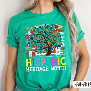 May include: A green t-shirt with a colorful tree design and the text "Hispanic Heritage Month".
