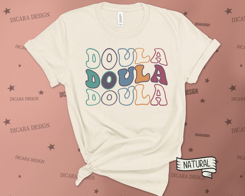 May include: A beige t-shirt with the word "DOULA" written three times in a retro font with colorful outlines. The word is stacked vertically with each word in a different color.