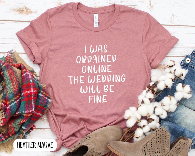 May include: Heather mauve t-shirt with the text "I was ordained online the wedding will be fine" printed in white.