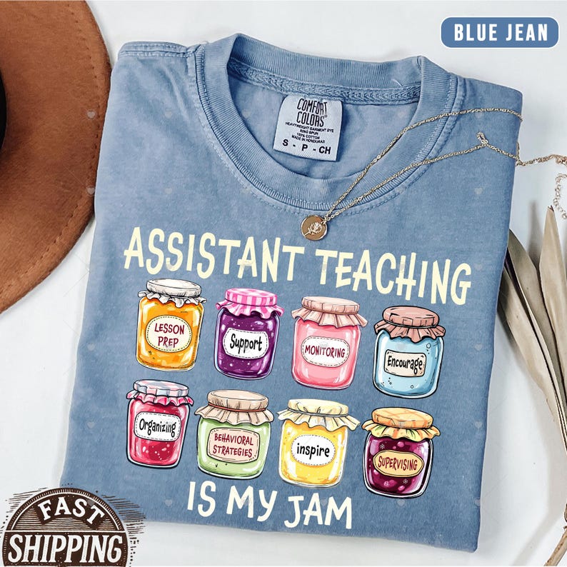 Puede incluir: Una camiseta azul jean con el texto "Assistant Teaching is my jam" y un gr&aacute;fico de tarros de mermelada con palabras como "Lesson Prep", "Support", "Monitoring", "Encourage", "Organizing", "Behavioral Strategies", "Inspire" y "Supervising".
