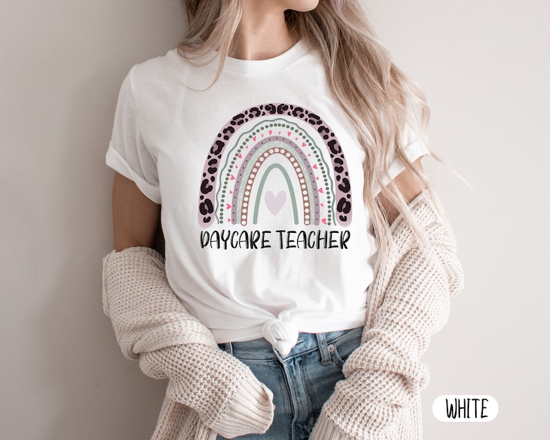 May include: White t-shirt featuring a rainbow design and the text "Daycare Teacher".