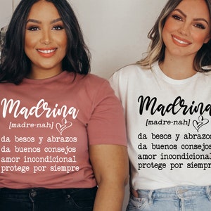 May include: Two women wearing white and pink t-shirts with the word "Madrina" and the definition "[madre-nah] da besos y abrazos da buenos consejos amor incondicional protege por siempre" printed on them.