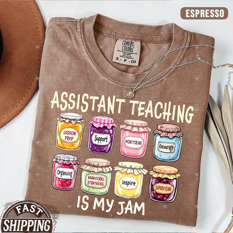 Puede incluir: Una camiseta marr&oacute;n con el texto "Assistant Teaching is my jam" y un gr&aacute;fico de tarros de mermelada con palabras como "Lesson Prep", "Support", "Monitoring", "Encourage", "Organizing", "Behavioral Strategies", "Inspire" y "Supervising" en ellos.