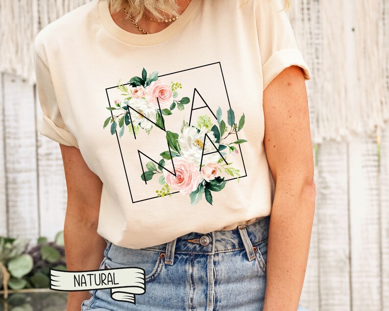 May include: A cream coloured t-shirt with a floral design and the word "NANA" in a black square.