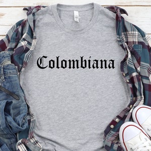 Op de afbeelding: Een grijs T-shirt met het woord "Colombiana" gedrukt in zwarte gotische letters.