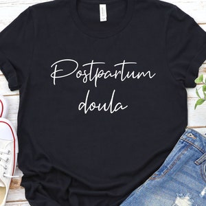 May include: Black t-shirt with white text that reads "Postpartum Doula".