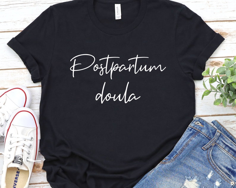May include: Black t-shirt with white text that reads "Postpartum Doula".