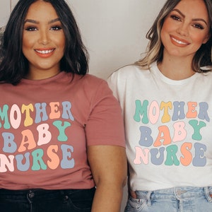 Może przedstawiać: Dwie osoby w koszulkach z napisem "Mother Baby Nurse" w kolorowej czcionce retro. Koszulki są r&oacute;żowe i białe.