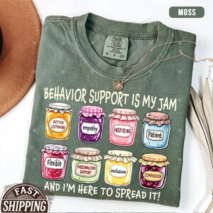 May include: A green t-shirt with the text "Behavior Support is My Jam" and a row of colorful jars with words like "Active Listening", "Empathy", "Inspiring", "Patient", "Flexible", "Personalized Support", "Inclusion", and "Compassion". The text "And I'm Here to Spread It!" is below the jars.