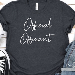 May include: A dark gray t-shirt with the text "Official Officiant" written in white cursive.